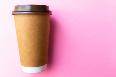 brown paper coffee cup on a bright pink backgroud. Simple flat lay with copy space. Minimal concept.の写真素材
