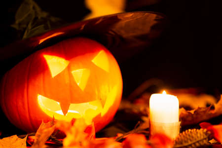 Halloween Still Life Colorful Theme Scary Decorated Dark and yellow maple leaves Room with Burning Pumpkin, Candlestick, Witch's Hat In Background yellow leavesの写真素材
