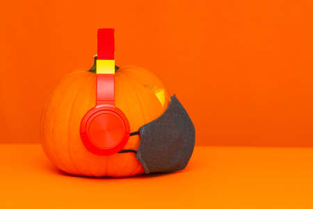 Side view Happy Halloween decorations festival and music concept background.Mix variety candle items face mask and pumpkin listening radio by headphone on orange background.の写真素材