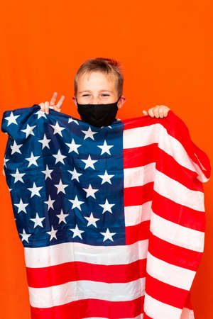 Attractive little boy with the flag of the United States, showing victory on a orange trendy backgroundの写真素材