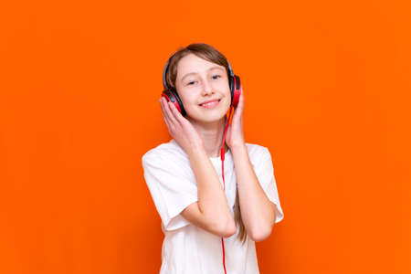 Attractive 12s girl in white t-shirt listens to music on red headphones closeup in a studio indoorの写真素材