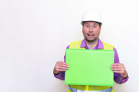 Portrait of curious architect in a construction helmet holding a folder, free place mock up blank...