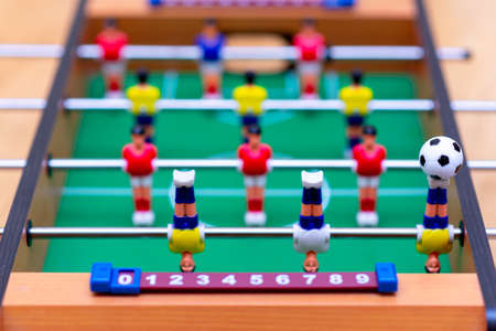 Close up table soccer with red yellow players and a ball.