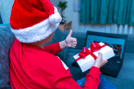 Back view kid boy shows thumb up Christmas through a video call with friends during pandemic...