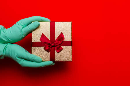 Gift box, hands in medical gloves.Copy space. Preparation for the holiday during the coronavirus...