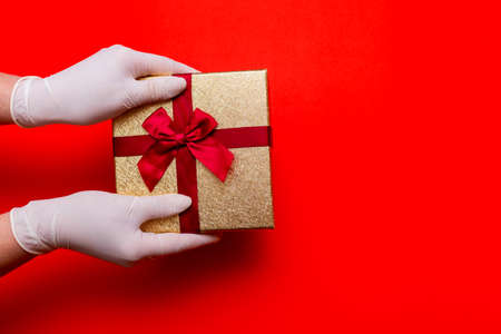 Gift box, hands in medical gloves.Copy space. Preparation for the holiday during the coronavirus pandemic.Top view.の写真素材