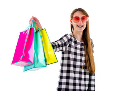 Happy teenage girl holding colored shopping bags over white studio background.Mock up copy space...