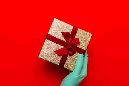 Gift box, hand in medical gloves.Copy space. Preparation for the holiday during the coronavirus pandemic.Top view.の写真素材