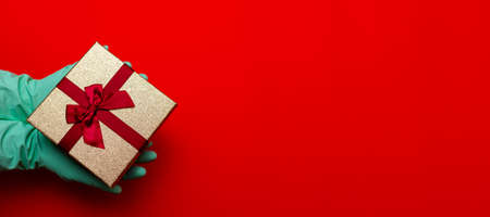 Panoramic view Gift box, hands in medical gloves.Copy space. Preparation for the holiday during the...