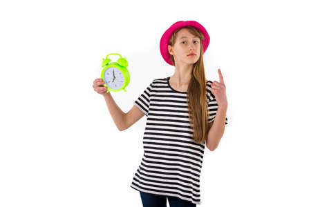 Teen Girl holding alarm Clock, isolated on white background. Portrait of caucasian teenager showing...