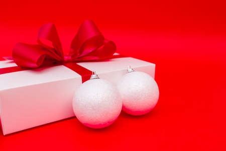 christmas gift and white balls on red bright backgroundの写真素材