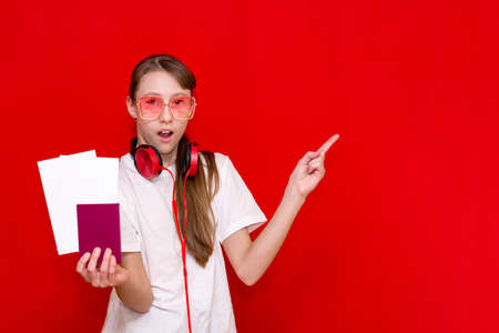 Beautiful teen Girl With Passport And Flight Tickets, on red studio background.Showing at copy space.の写真素材