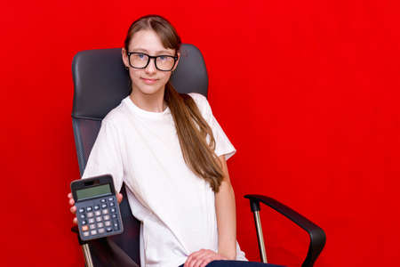 Young caucasian girl counting calculator. Education concept.Red studio background.の写真素材