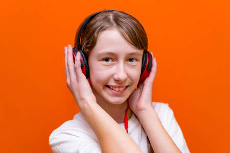Attractive 12s girl listens to music on red headphones closeup in a studio indoorの写真素材