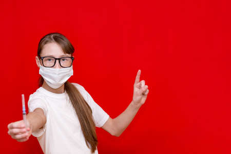 Teenage girl coronavirus medical mask with a syringe in his hands.Studio shot.Copy space.