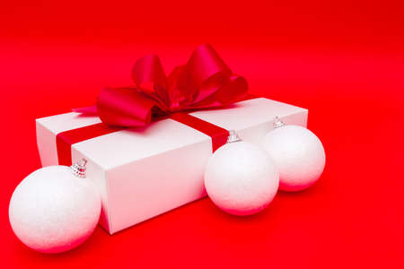 christmas gift and white balls on red bright backgroundの写真素材