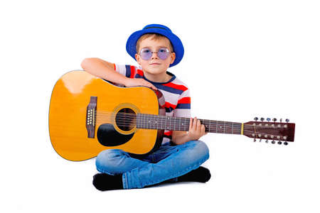 A boy kid holding guitar on a white background in the studio.の写真素材