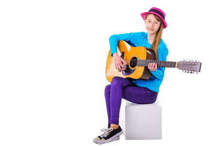 A girl kid plays guitar on a white background in the studio.Copy spaceの写真素材