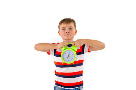 Attractive cute boy holding alarm clock on white isolated studio background.の写真素材