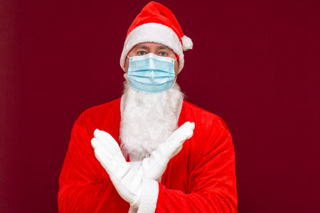 Closeup santa claus costume rejection expression crossing arms and palms doing negative sign,wears medical mask.Front view image.の写真素材