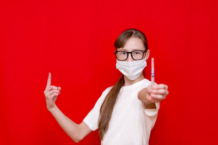 Teenage girl coronavirus medical mask with a syringe in his hands.Studio shot.の写真素材