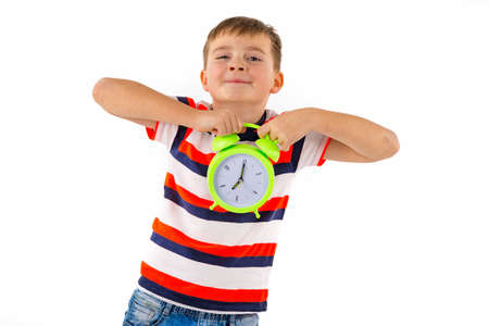 Attractive cute boy holding alarm clock on white isolated studio background.の写真素材