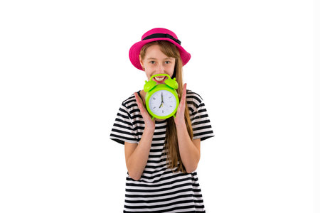 Teen Girl holding alarm Clock, isolated on white background. Portrait of caucasian teenager showing green alarm clock.の写真素材