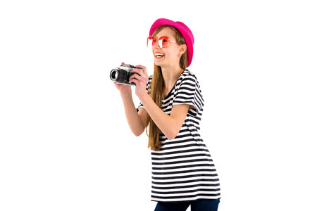 Happy hipster girl holding vintage camera in studio white isolated background.Side viewの写真素材