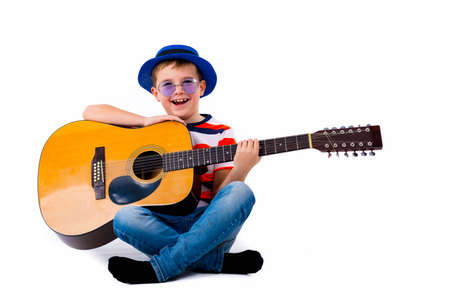 A boy kid holding guitar on a white background in the studio.の写真素材
