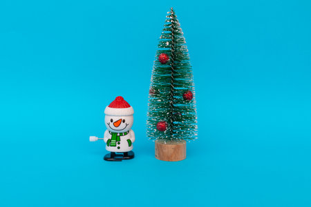 One toy snowman and christmas tree on blue background copy space. Merry Christmas and Happy New Year.の写真素材