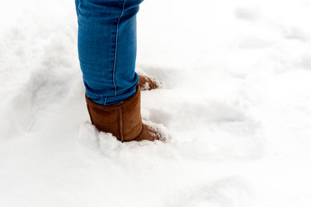 Warm winter boots in snow.Female feets in brown shoes, winter walking in snow.Side view of standing female legs with snowy boots.Copy space.の写真素材