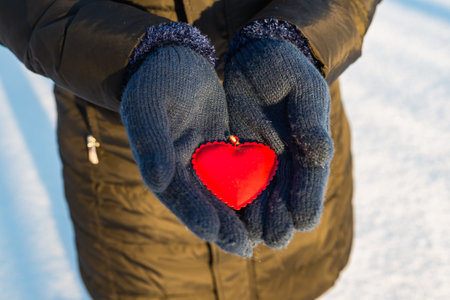 Woman hands in blue gloves holding red heart. Winter outdoors valentines day timeの写真素材