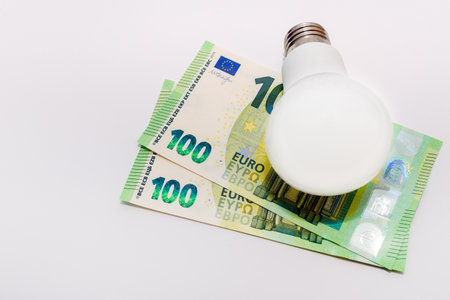 One LED bulb and 100 euro bills on white light backgroundの写真素材