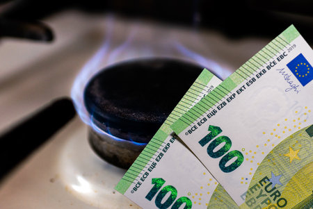 Money and stove.Burning stove flame and one hundred bills two denominations.Close up.の写真素材