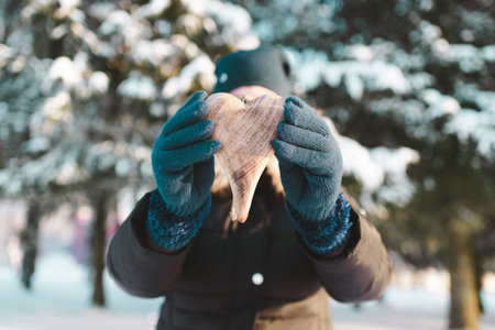 Woman behind a wooden heart against conifers blurry background.の写真素材