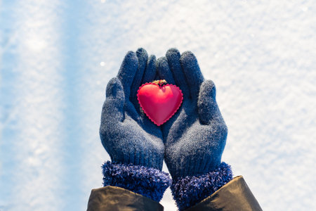Woman hands in blue gloves holding red heart. Winter outdoors valentines day timeの写真素材