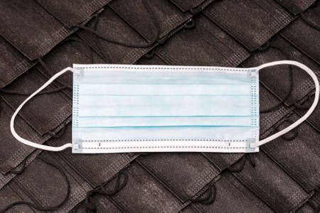 Pile of black face masks with one blue mask.top view flat lay.