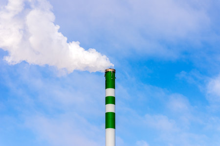 One Industrial smoke pipe from chimney on blue cloudy sky.White smoke emanates from the pipe.の写真素材