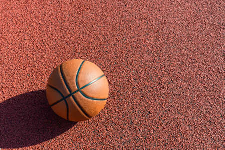 Orange ball for basketball lying on the sport court.Sport red court outdoor .Copy space.Top view.の写真素材