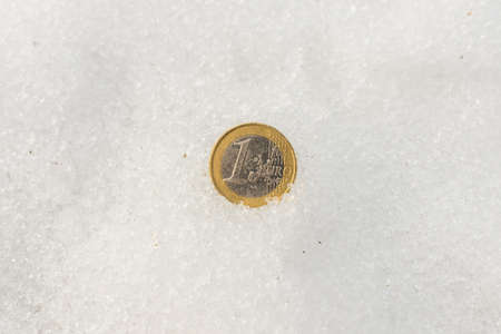 One euro coin flat lay on a snow. The concept of the economy crisis.Copy space.