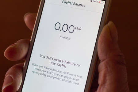 Paypal showing zero balance on smartphone screen.Tiredness Woman holding phone with 0...