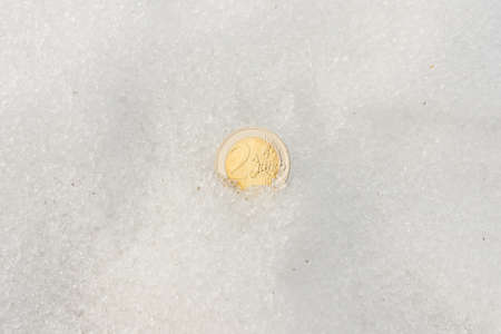 Two euro coin flat lay on a snow. The concept of the economy crisis.Copy space.