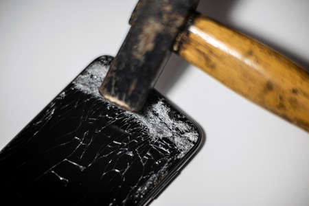 Hammer and smart phone with a broken screen.Electronics repair service. Crash smartphone.Indoors shot.の写真素材