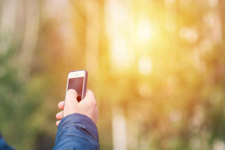 One man with his mobile smart phone searching for reception signal in the spring sunny forest.の写真素材
