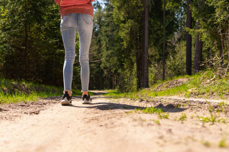 One Girl tourist with a backpack along the road in the woods.Summer day.Cropped image.の写真素材