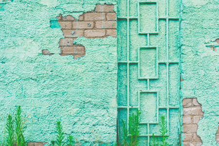 Paint green wall grill rustic old background.building green wall with a door metal grill.a crumbling wall overlooks the bricks on a summer day.Closeup.の写真素材