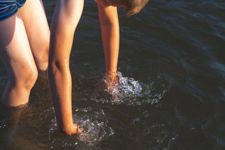 Young kid boy play in water and making splash boy to prepare in lake or river and have fun with drops.Closeup.の写真素材