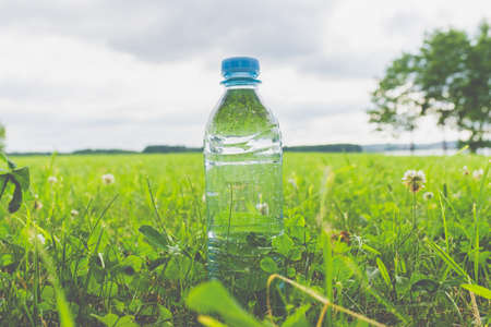 Plastic Bottle with fresh transparent water on green grass on sunny summer day.Nature texture, green blurred background, wallpaper.の写真素材