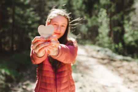 One joyful teen girl in forest holding a wooden heart in her hands.On spring or summer nice sunny...