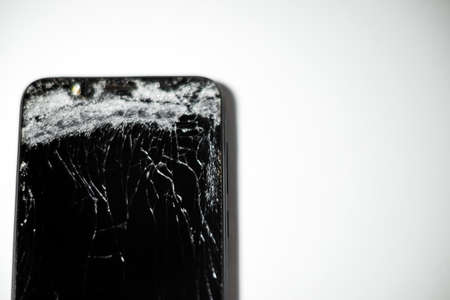 Mobile phone with broken screen on white background.Closeup.